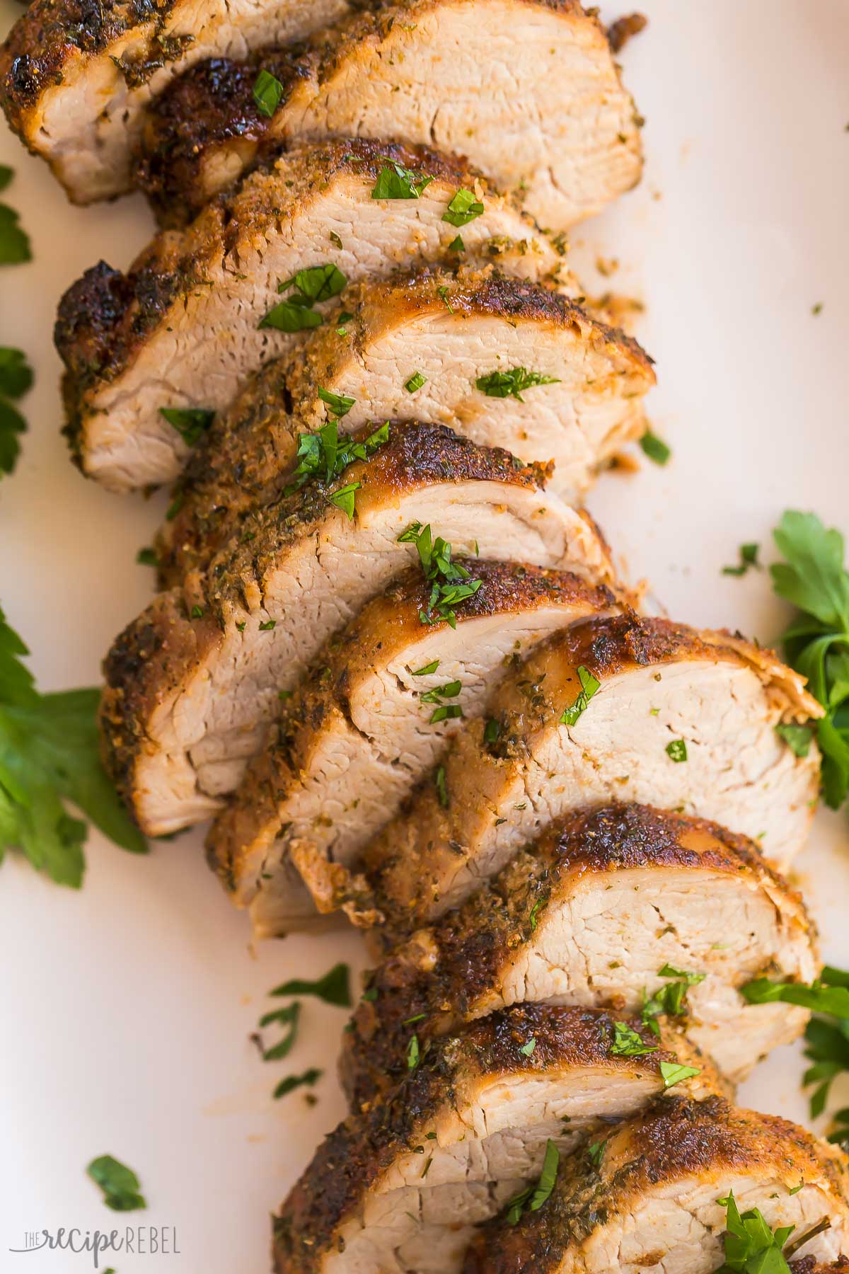 close up image of sliced air fryer pork tenderloin with fresh parsley