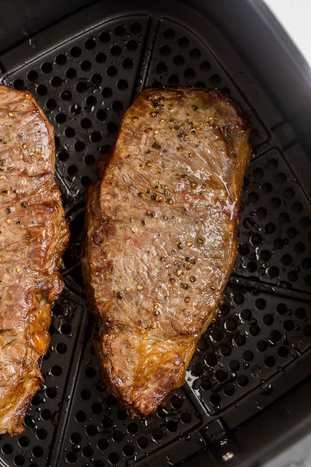 two cooked steaks in air fryer