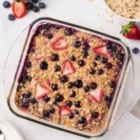 overhead image of baked oatmeal with berries and oats on the side