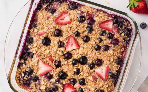 overhead image of baked oatmeal with berries and oats on the side