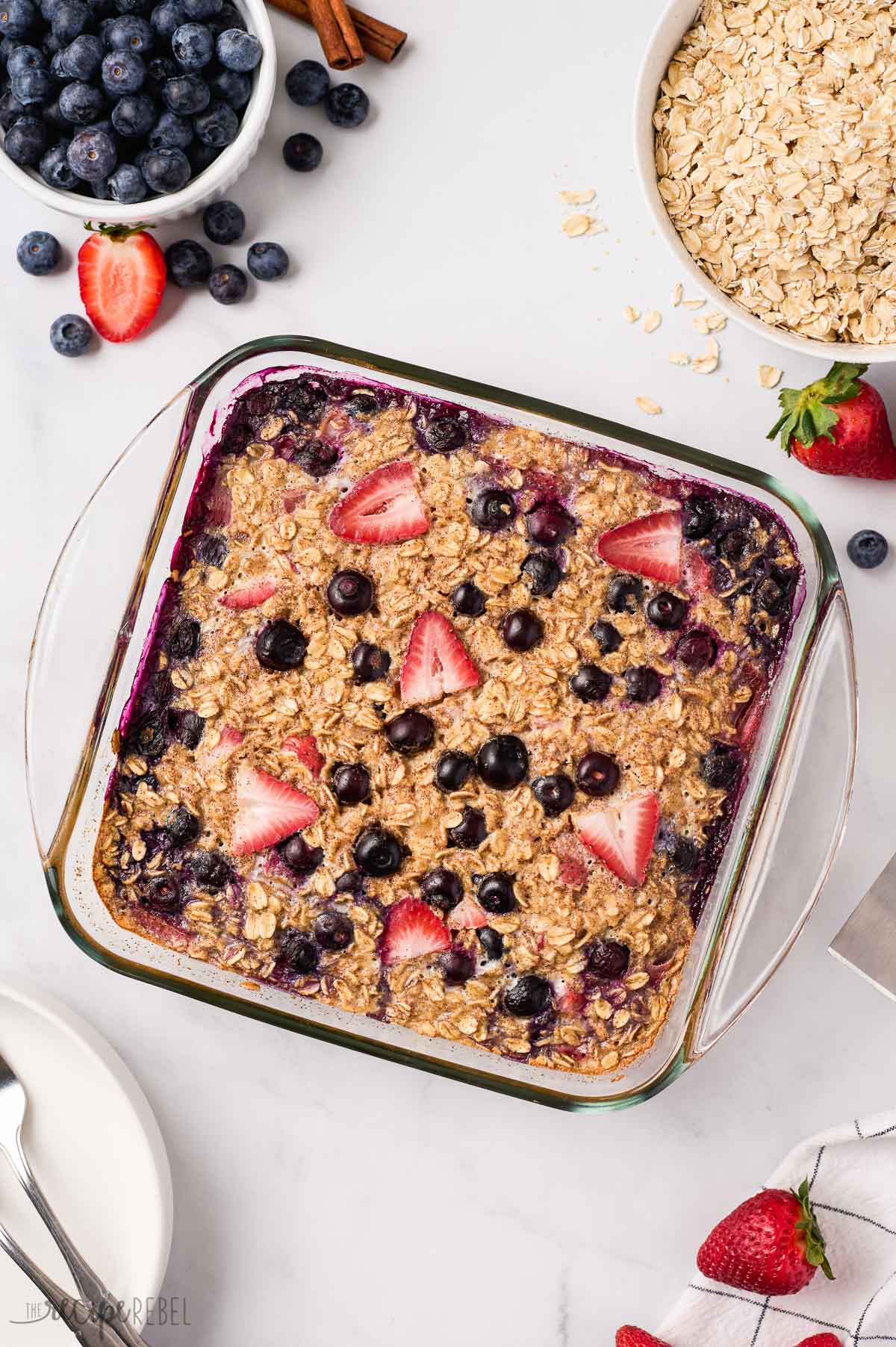 overhead image of baked oatmeal with berries and oats on the side