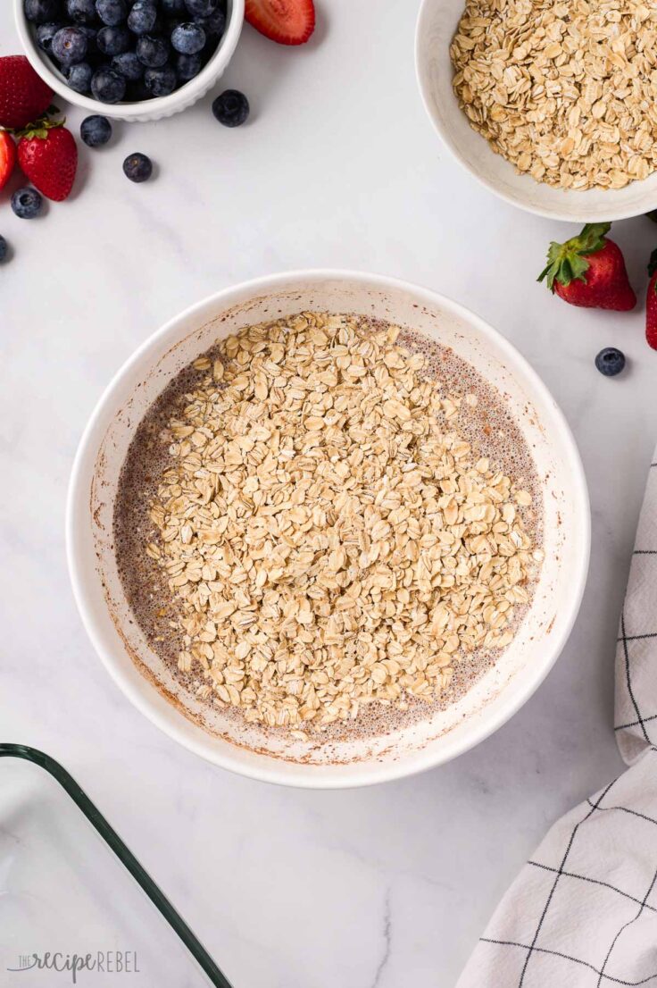 oats added to wet ingredients in white bowl