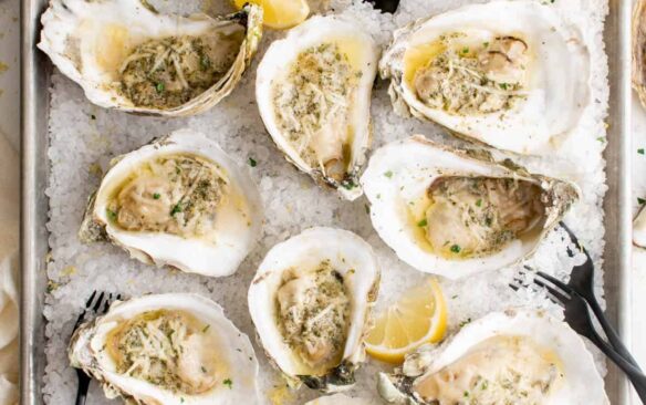 Baked oysters on a bed of ice with lemon wedges.