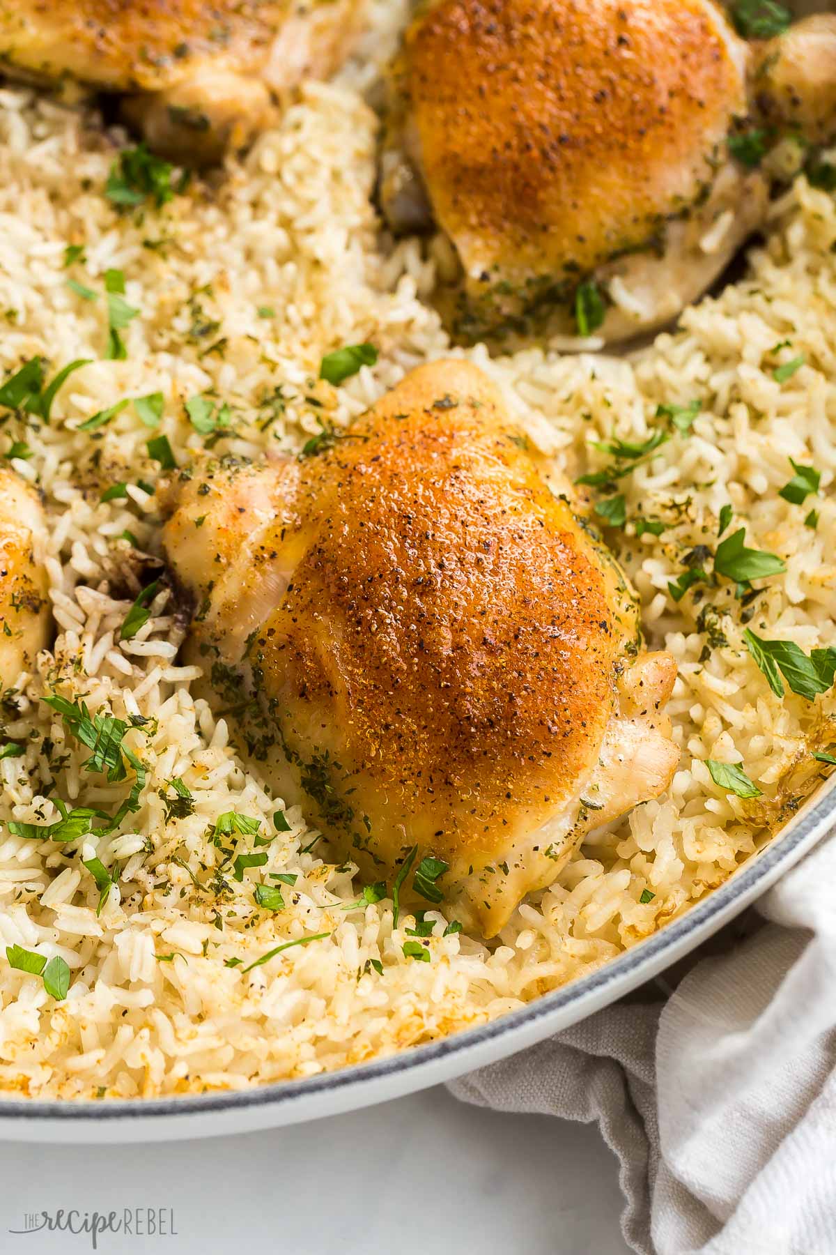 close up image of crispy chicken thigh on a bed of rice in pan