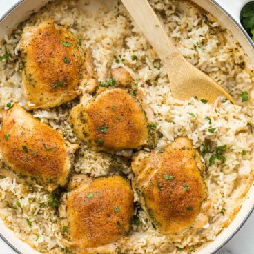 overhead image of baked chicken and rice in large white pan