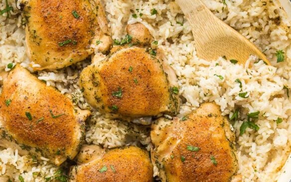 overhead image of baked chicken and rice in large white pan