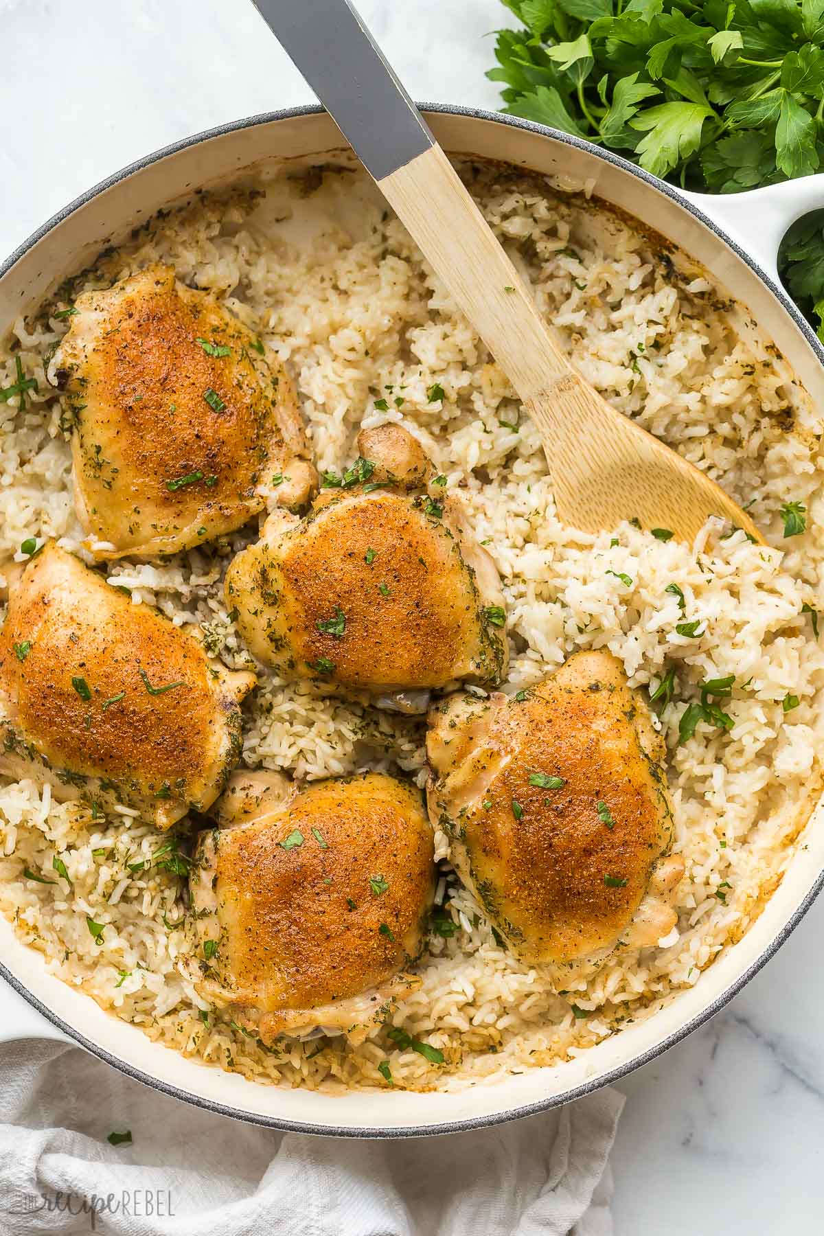 overhead image of baked chicken and rice in large white pan