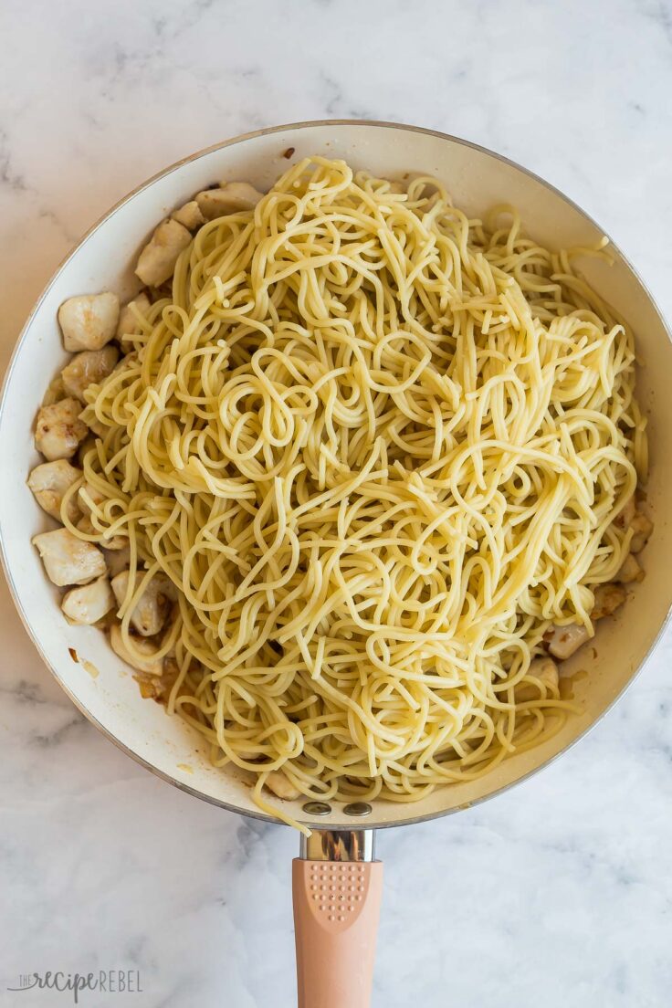 cooked spaghetti noodles added to chicken in pan