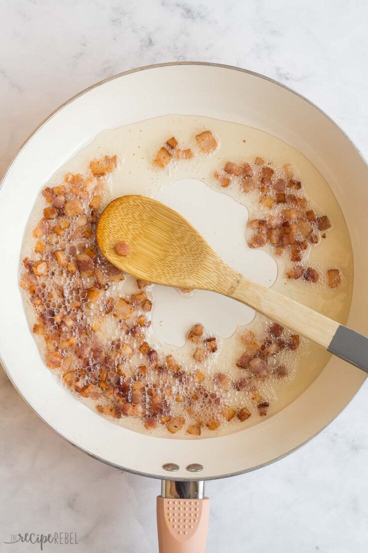 bacon cooked in pan with wooden spoon on the side