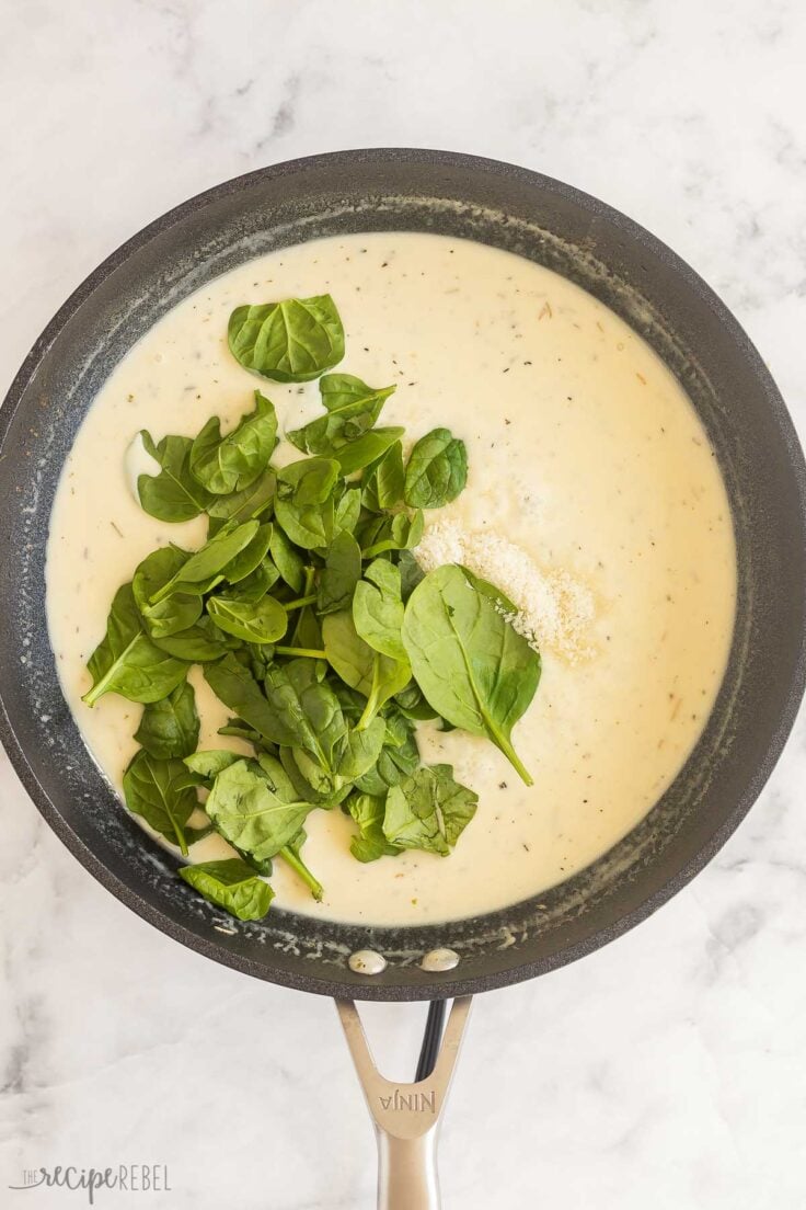 fresh spinach added to cream sauce in skillet