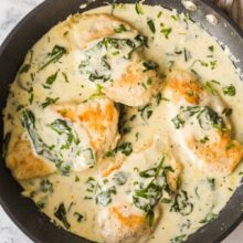 overhead image of four chicken breasts in pan with florentine sauce