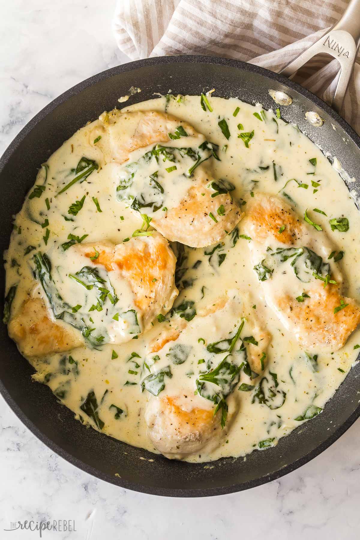 overhead image of four chicken breasts in pan with florentine sauce
