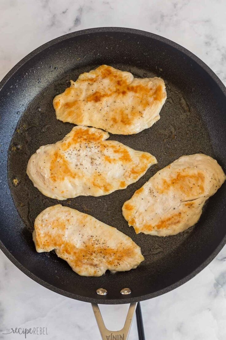 overhead image of four browned chicken breast in black skillet