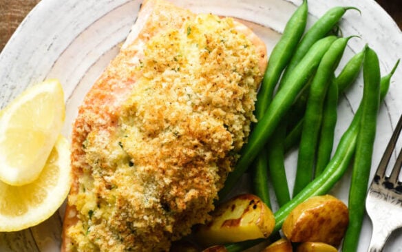 Crab stuffed salmon served on a plate with green beans and potatoes.