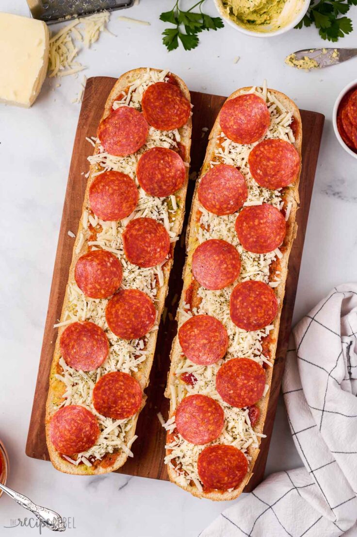 cheese and pepperoni added to french bread pizza ready to bake