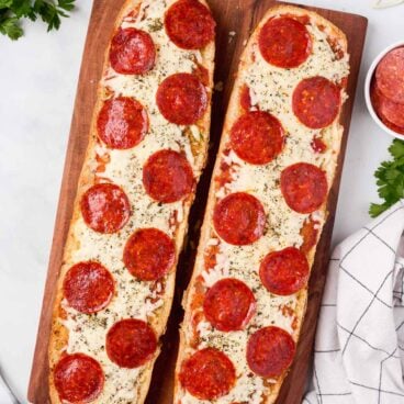 overhead image of two halves of french bread pizza on a cutting board