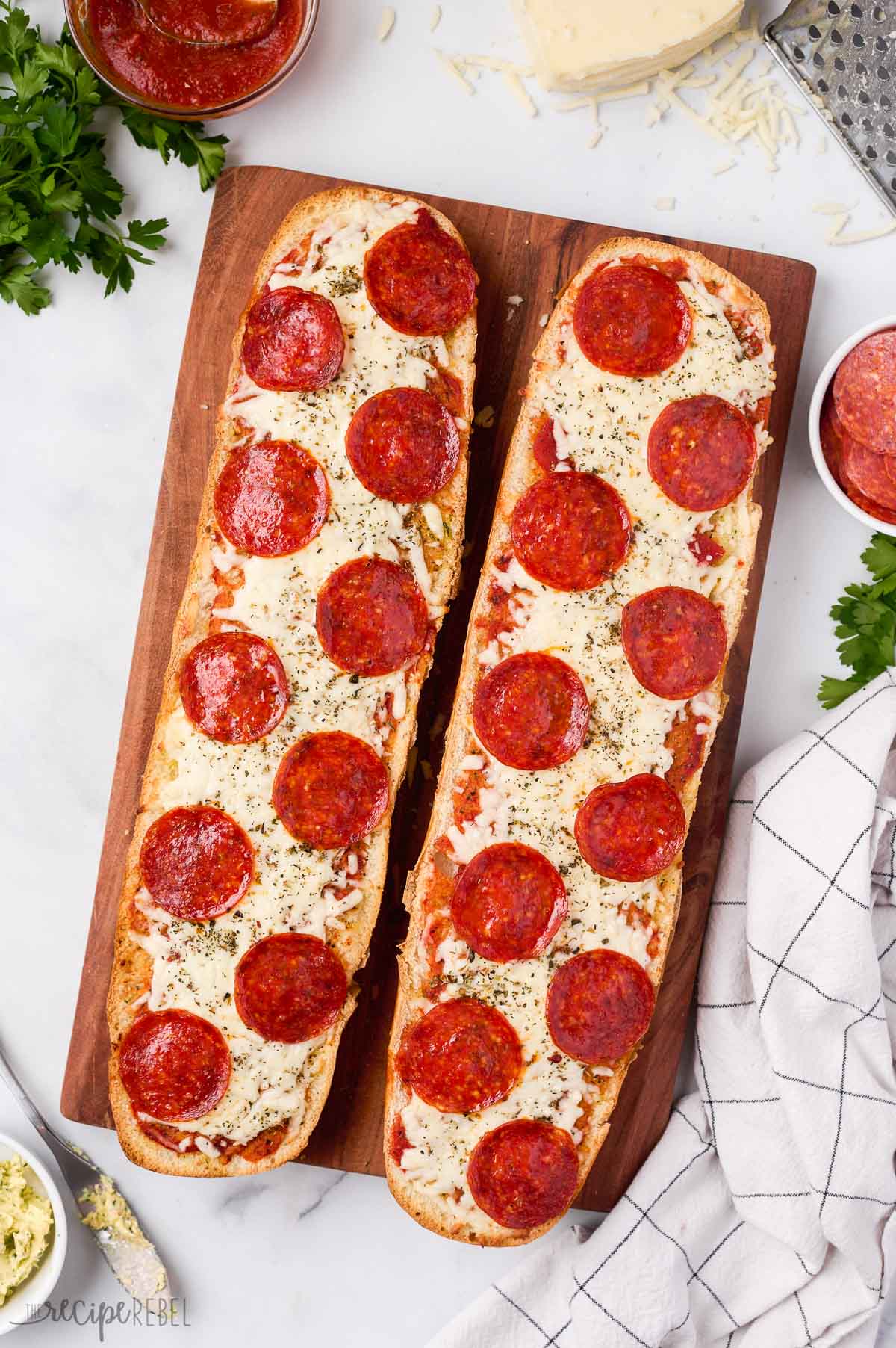 overhead image of two halves of french bread pizza on a cutting board