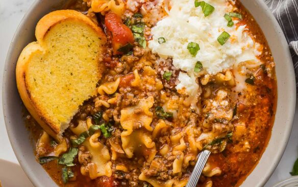 square overhead image of lasagna soup in bowl with cheese and garlic bread