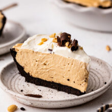 slice of peanut butter pie on grey plate with whipped cream.