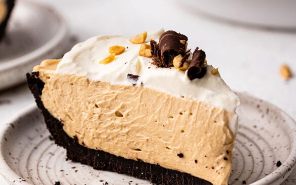 slice of peanut butter pie on grey plate with whipped cream.
