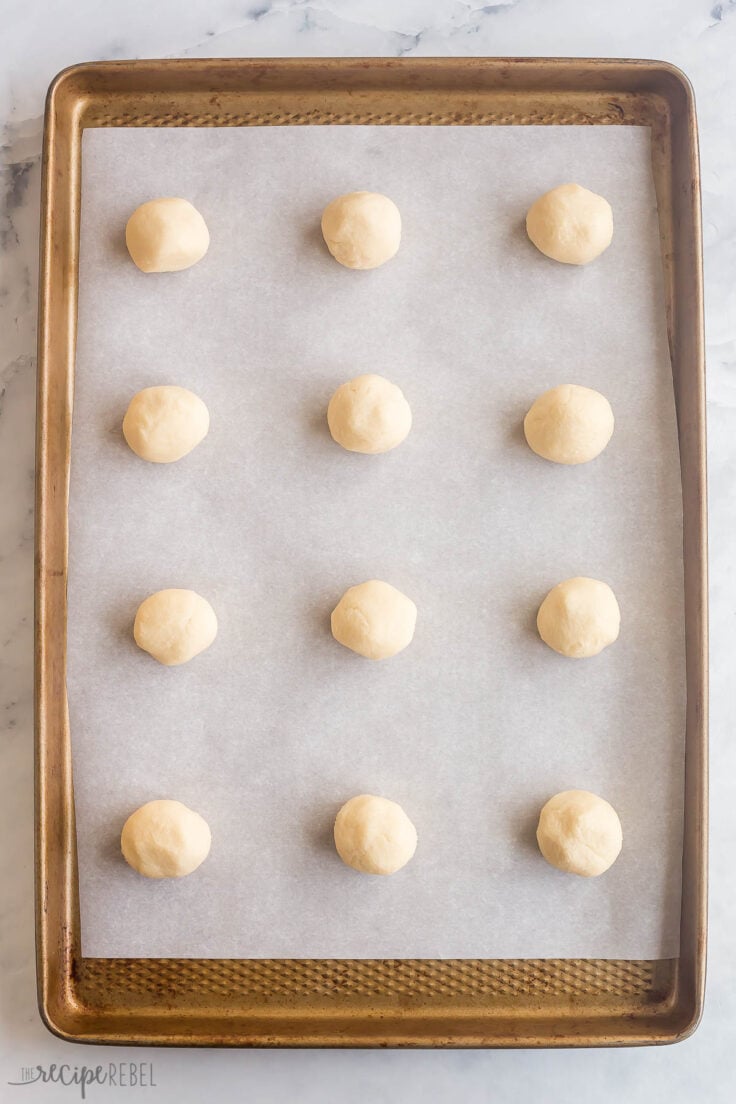 sugar cookie dough rolled into balls on parchment lined baking sheet