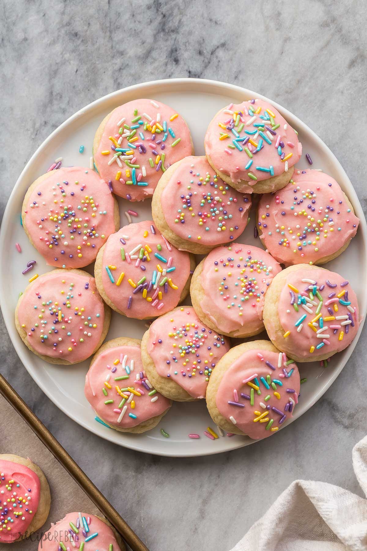 overhead image of frosted sugar cookies with pink frosting and sprinkles