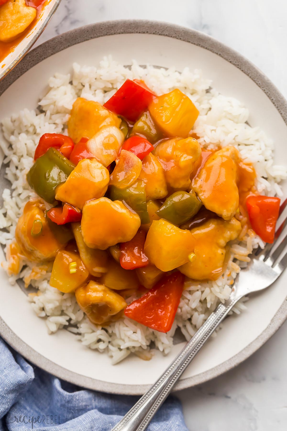 sweet sour chicken with pineapple and peppers on plate of rice