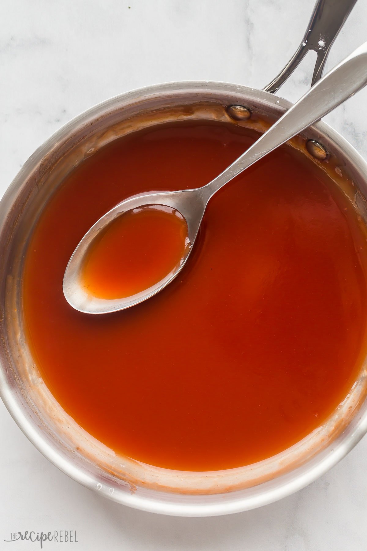 overhead image of sweet and sour sauce in steel skillet with serving spoon