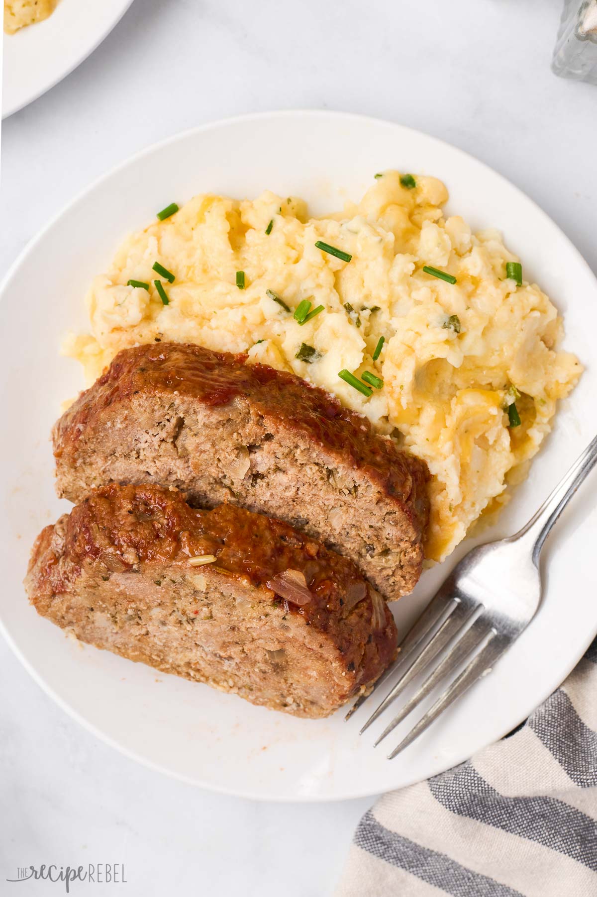 two slices of turkey meatloaf on a plate with mashed potatoes
