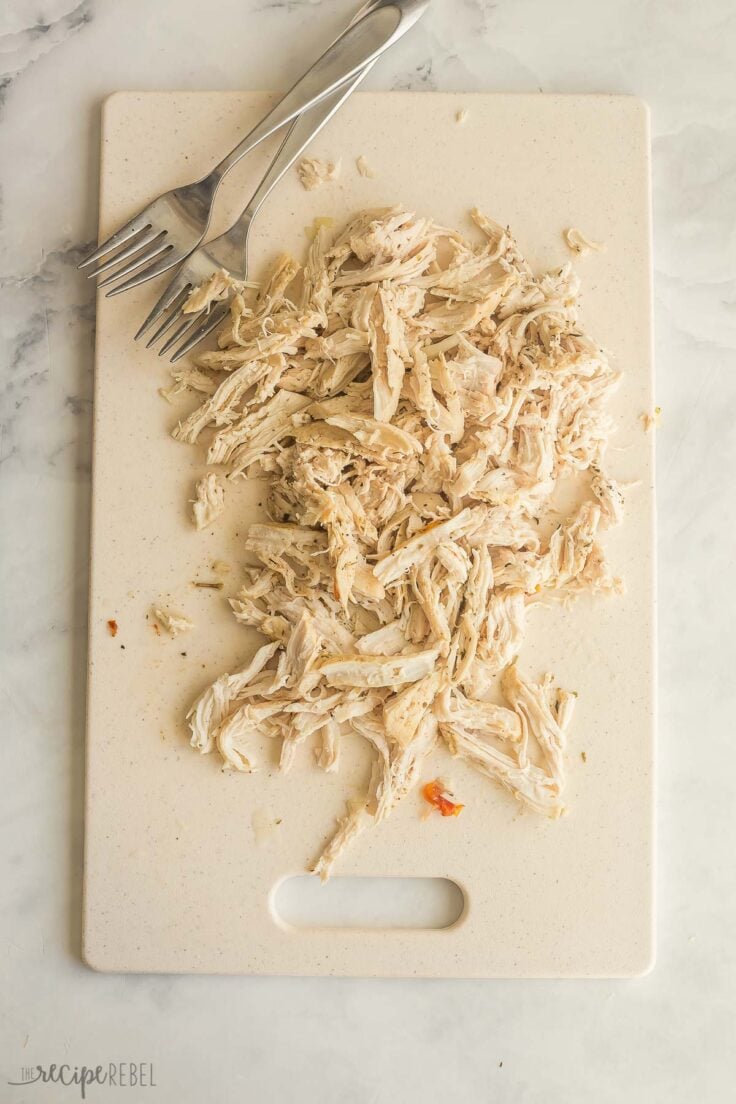 shredded chicken on a cutting board with two forks