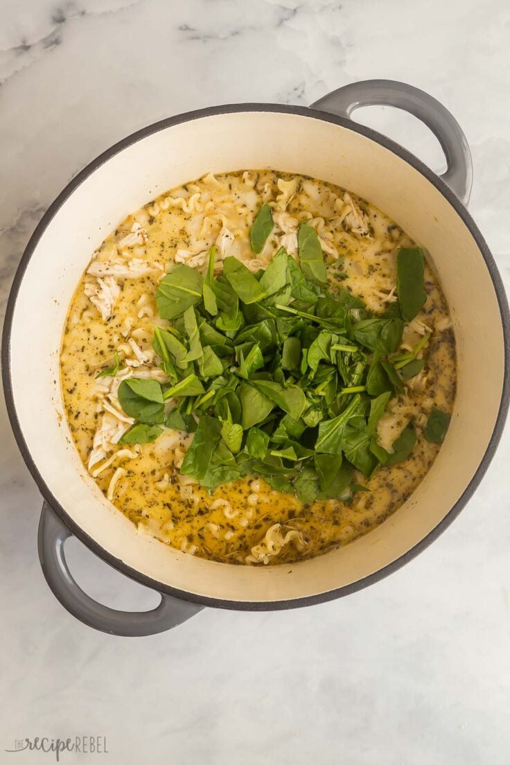 fresh spinach added to white lasagna soup in pot