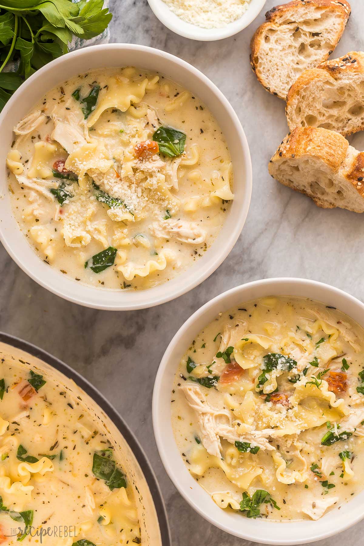 two bowls of white lasagna soup with crusty bread on the side