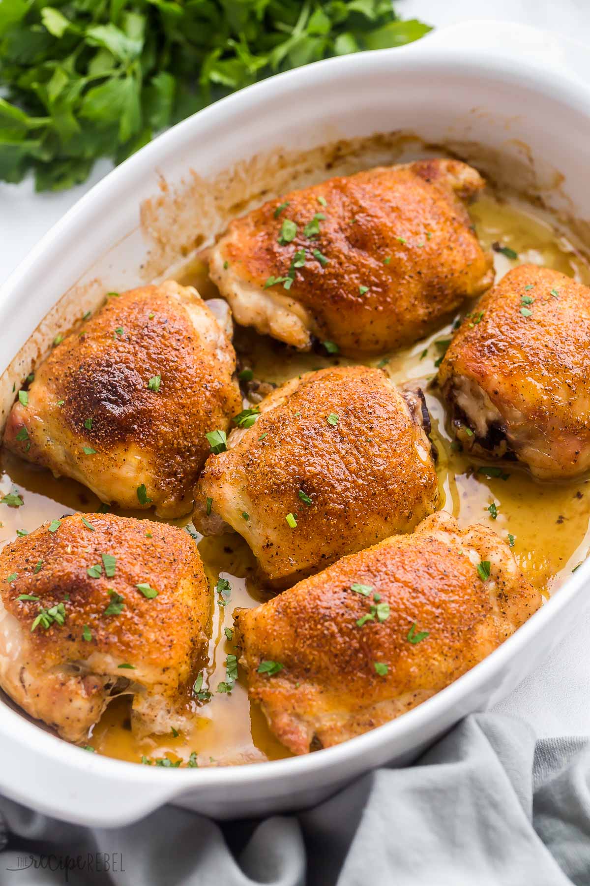 close up image of baked bone in chicken thighs in white baking dish