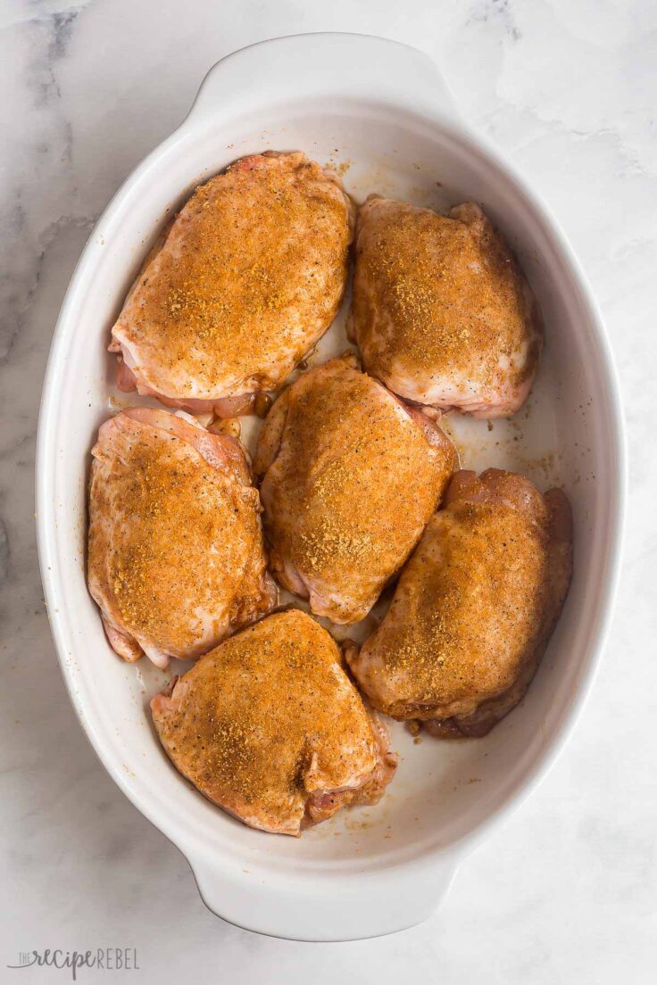 bone in chicken thighs rubbed with seasoning in baking dish