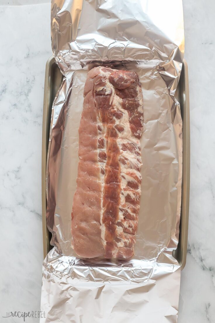 uncooked rack of ribs on foil on sheet pan