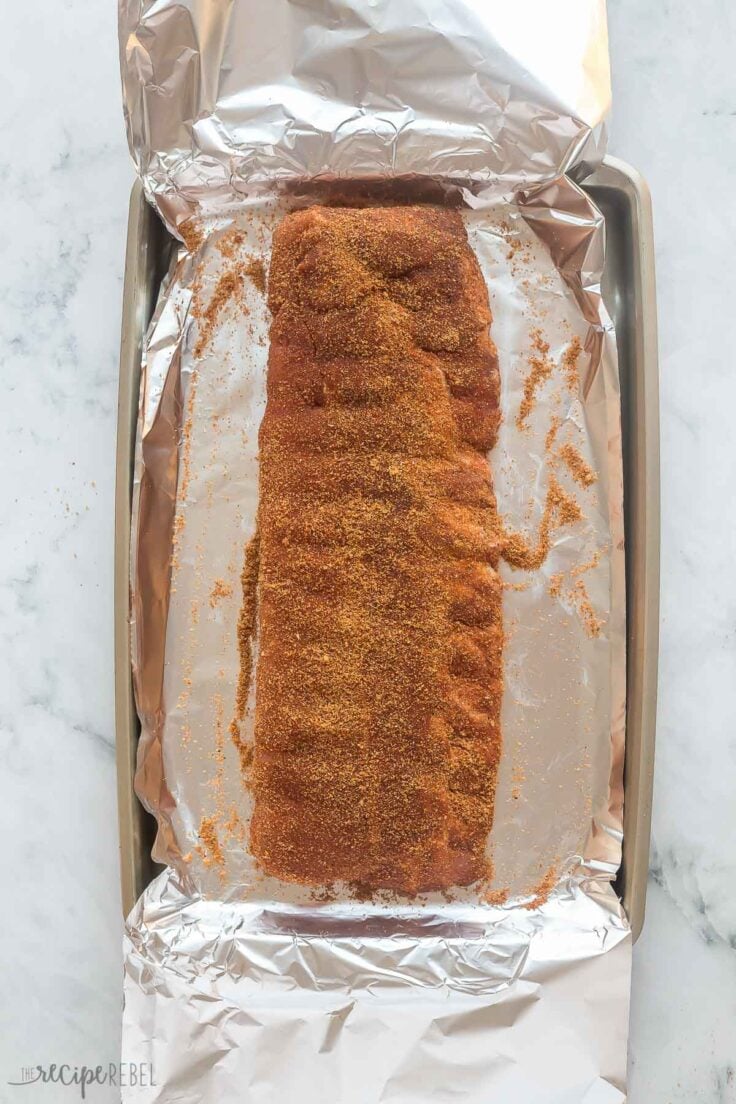 ribs rubbed with seasoning on foil on baking sheet