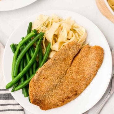 overhead image of baked tilapia with green beans and noodles