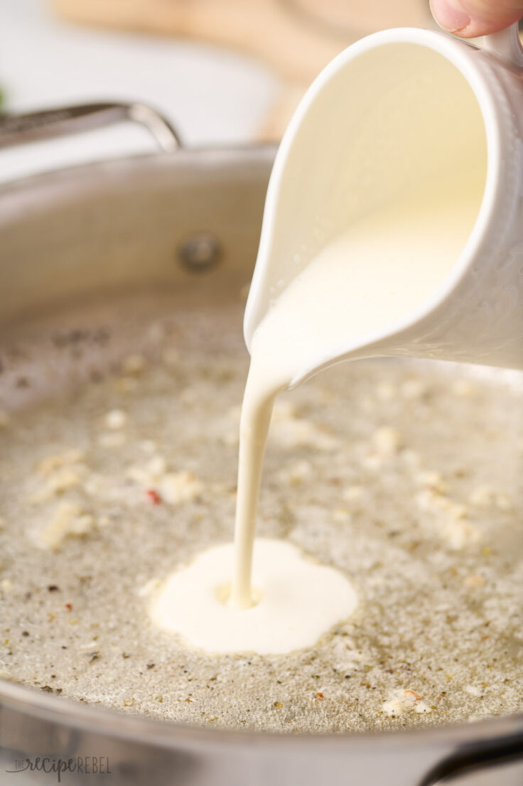 cream being added to sauteed spices in pan