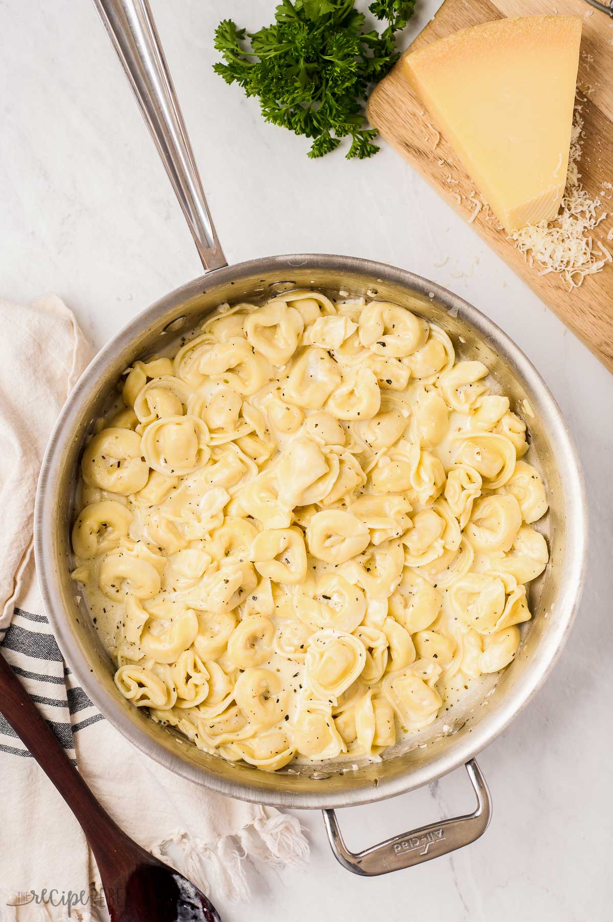 overhead image of creamy cheese tortellini in pan with parmesan and parsley