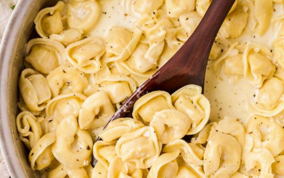 close up overhead image of cheese tortellini in creamy sauce in pan