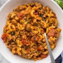 overhead image of american goulash recipe in white bowl with fork