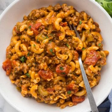 overhead image of american goulash recipe in white bowl with fork