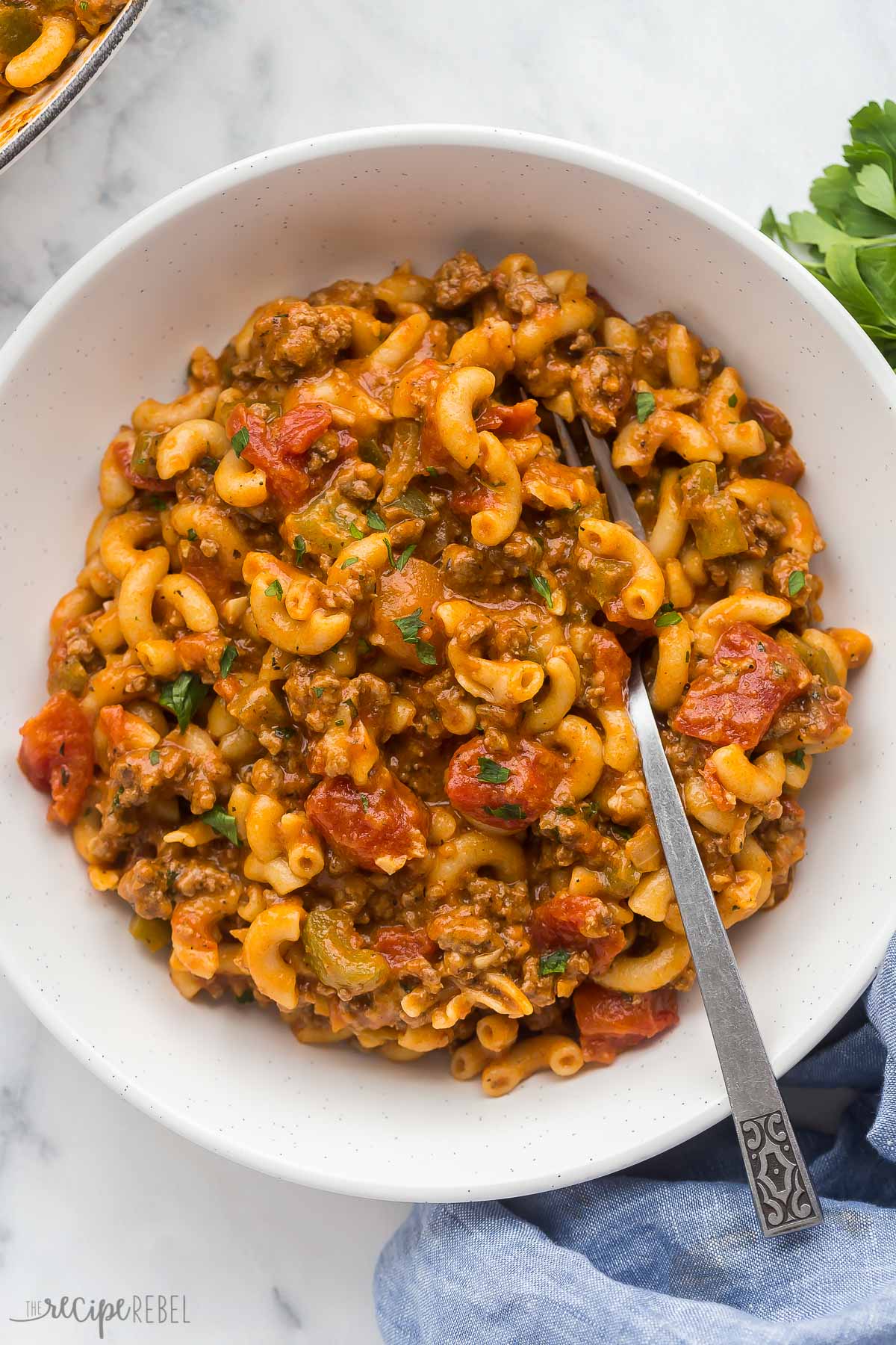 overhead image of american goulash recipe in white bowl with fork