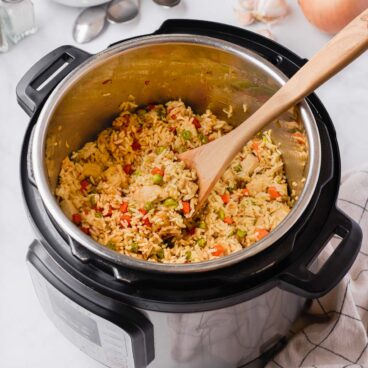 chicken and rice in instant pot with wooden spoon stuck in