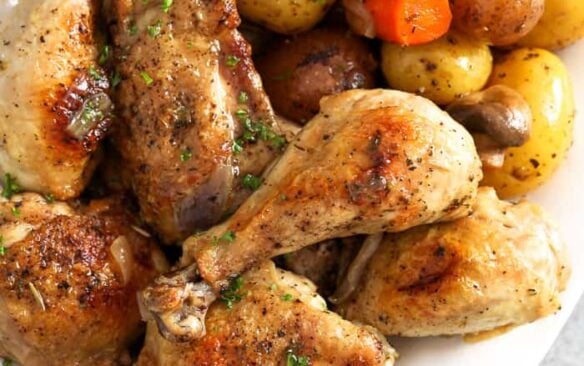 Chicken drumsticks served next to vegetables.