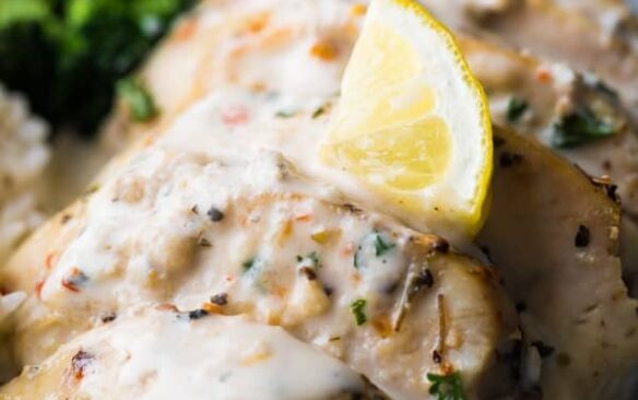 Creamy lemon chicken breasts topped with a lemon wedge.