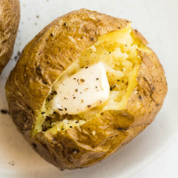 close up image of baked potato made in the microwave with butter