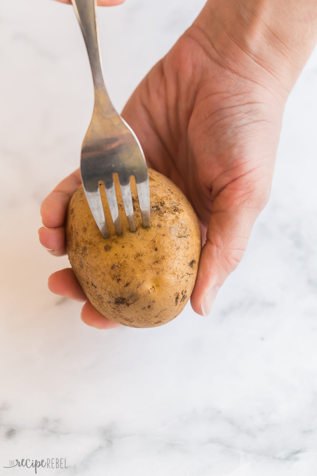 fork poking russet potato for microwave baked potato