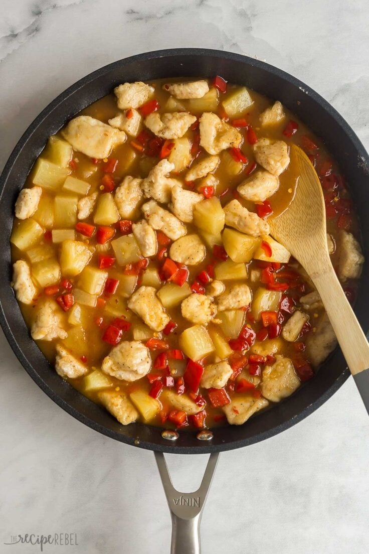 chicken pieces with sauce pineapple and peppers added to skillet