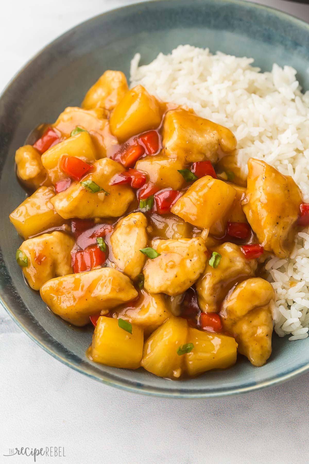 close up image of pineapple chicken on blue plate with white rice